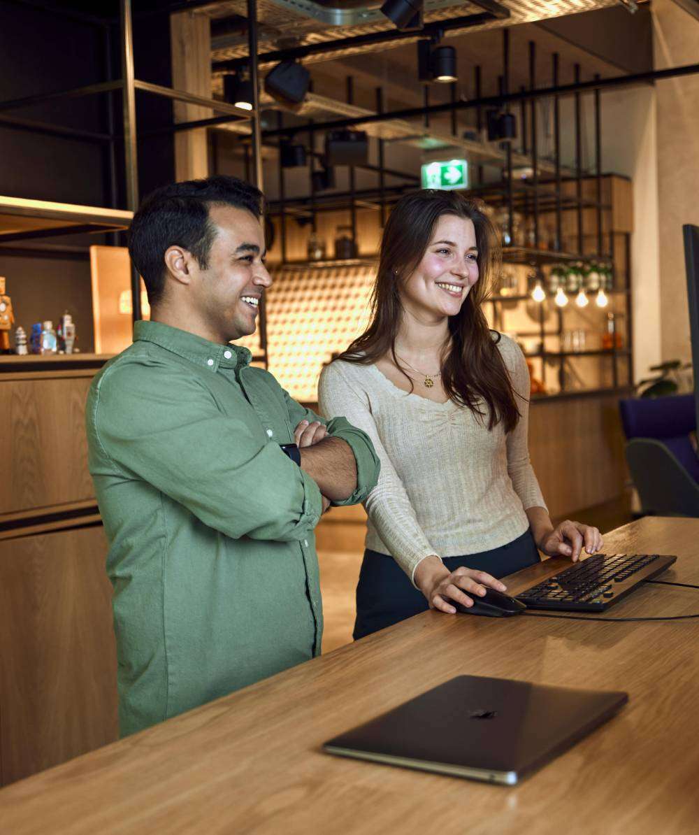 Smiling colleagues look at screen.
